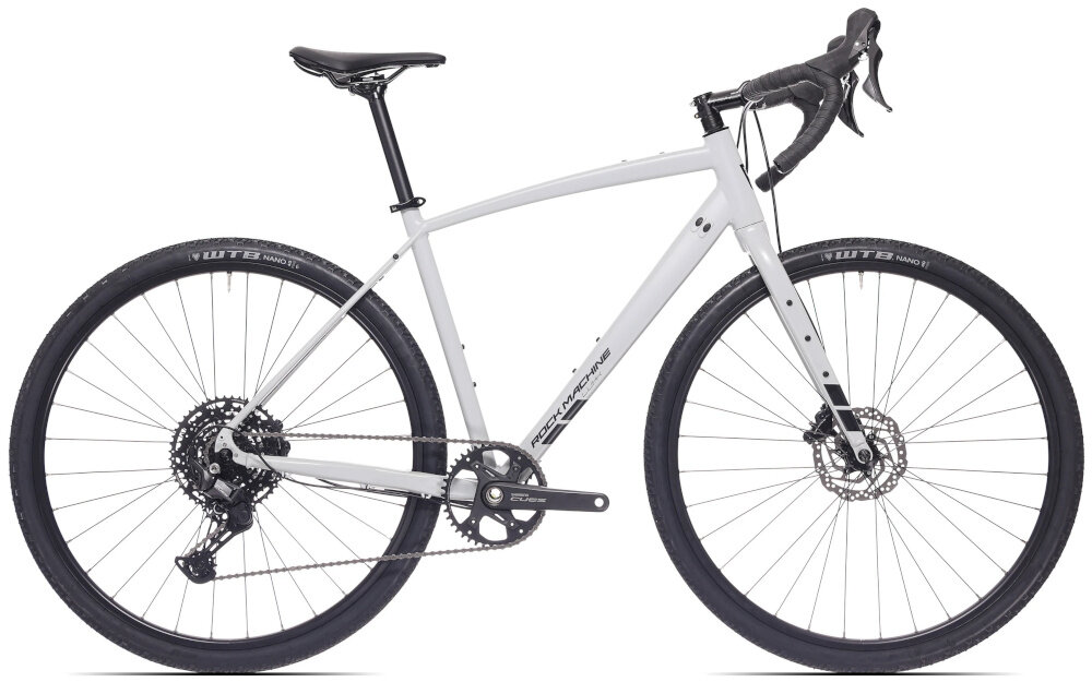Rower gravel ROCK MACHINE Lukk 50 U22 28 cali Szary rower na białym tle widoczny z boku do jazdy asfaltowej z trasami szutrowymi leśnymi drogami nierównymi ścieżkami poza miastem konstrukcja typu gravel szybkość roweru szosowego stabilność komfort wszechstronny charakter roweru