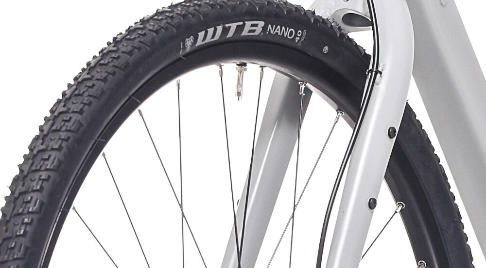 Rower gravel ROCK MACHINE Lukk 50 U22 28 cali Szary zbliżenie na oponę białe tło rozmiar koła 28 cali łatwiej jest pokonać różne przeszkody opony marki WTB obręcze marki Stars J20 piasty SHIMANO typu HB-QC300 regularne sprawdzanie ciśnienia powietrza wartość na bocznej części opony