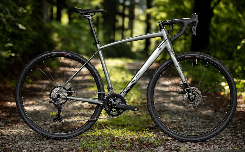 Rower gravel ROCK MACHINE Lukk 40 U22 28 cali Zielony las ścieżka rower widoczny bokiem w tle drzewa pasja hobby lekkość wszechstronność