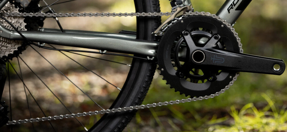Rower gravel ROCK MACHINE Lukk 40 U22 28 cali Zielony rozmazane tło zbliżenie na łańcuch łańcuch SHIMANO typu CN-LG500 do różnych napędów płynne przenoszenie mocy z pedałów na koła wysoka odporność na zużycie