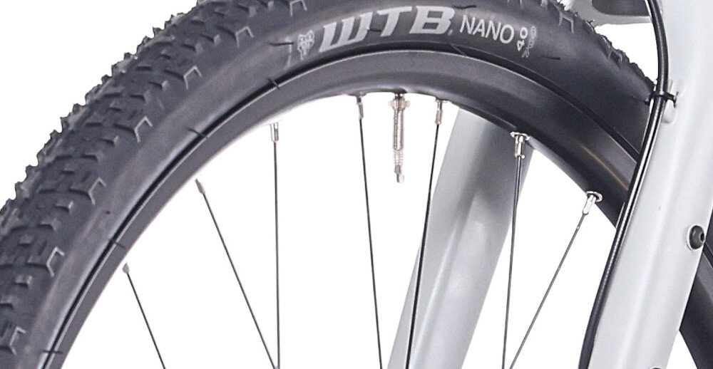 Rower gravel ROCK MACHINE Lukk 20 Flat Bar U22 28 cali Szary mat zbliżenie na oponę białe tło rozmiar koła 28 cali łatwiej jest pokonać różne przeszkody opony marki WTB obręcze marki Stars J20 piasty SHIMANO typu HB-QC300 regularne sprawdzanie ciśnienia powietrza wartość na bocznej części opony