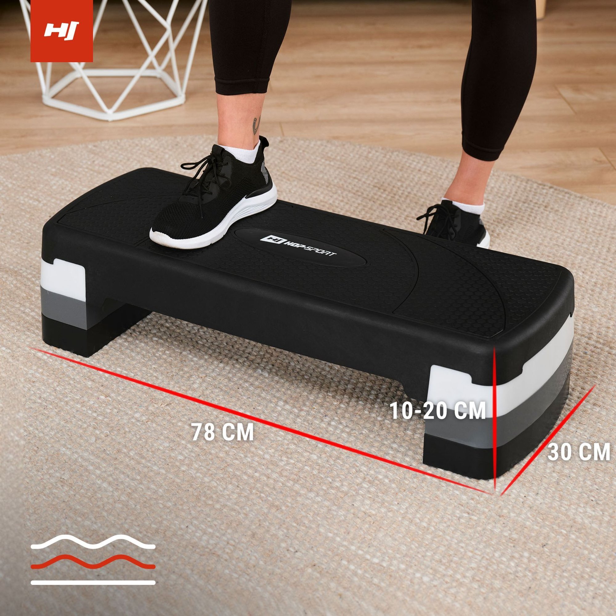Czarno-biały step do ćwiczeń z logo \'HOP SPORT\' na środku, z jedną stopą w czarnym bucie sportowym na powierzchni. Wymiary stepu to 78 cm długości, 30 cm szerokości i regulowana wysokość 10-20 cm.