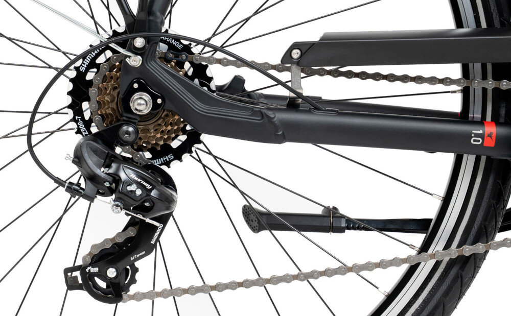 Zdjęcie przedstawia tylną część roweru z widocznym mechanizmem przerzutki i łańcuchem. Na przerzutce widoczny jest napis \'SHIMANO\'.