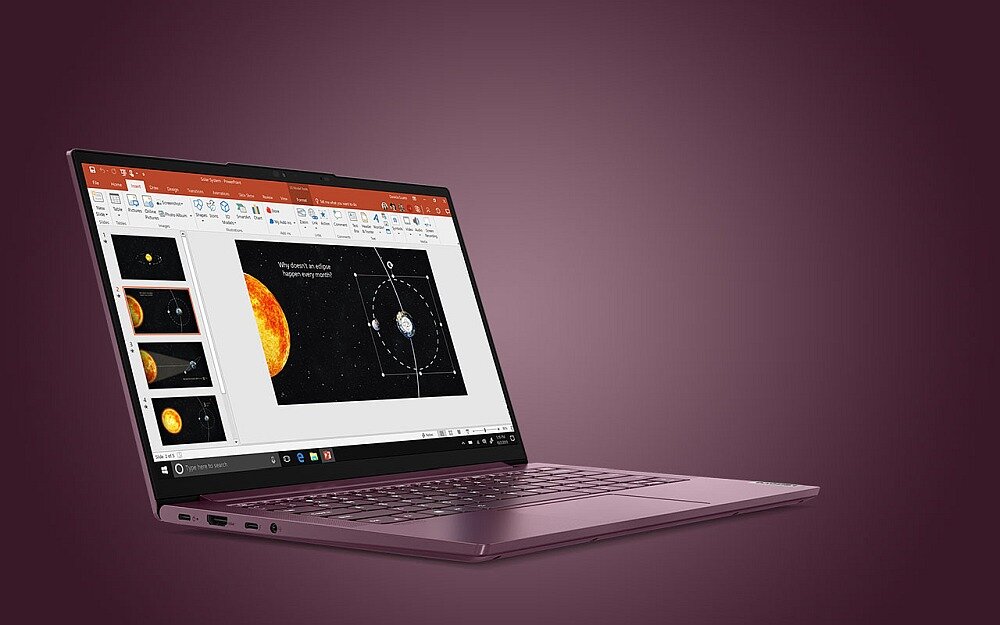 Na obrazie widoczny jest otwarty laptop z wyświetlonym na ekranie programem do prezentacji, pokazującym grafikę z planetami i słońcem. Laptop ma metaliczną obudowę i jest ustawiony na fioletowym tle.