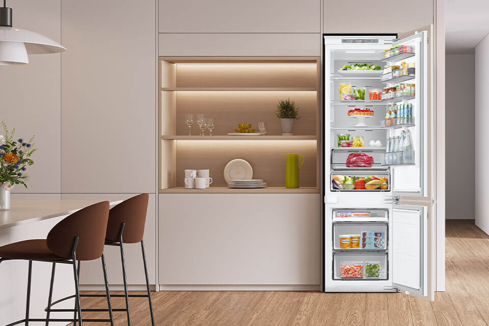 lodówka do zabudowy BRB80F30BEF0EO dostępna w Rtv Euro Agd Wnętrze nowoczesnej kuchni z otwartą lodówką wypełnioną różnorodnymi produktami spożywczymi. Obok lodówki znajduje się zabudowa z półkami, na których stoją naczynia i dekoracje.
