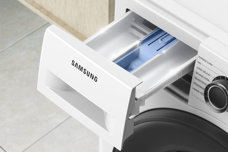 Widoczna jest otwarta szuflada na detergenty w pralce z logo \'SAMSUNG\'. Obok znajduje się pokrętło z widocznymi napisami: \'EXPRESS 15 MIN\', \'MIX\', \'LAINE/DELICAT\', \'SECHAGE COTON\', \'SECHAGE SYNTHETIQUE\', \'DESODORISATION\', \'LINGE SEC\'.
