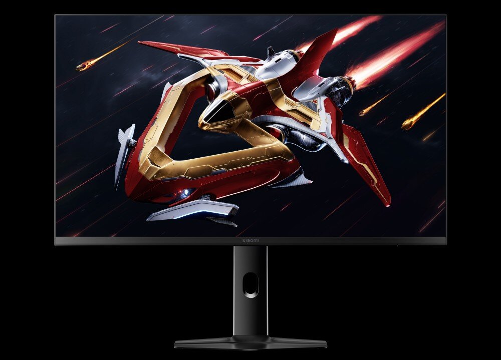 Monitor XIAOMI G Pro 27Qi Monitor wyświetla czerwoną i złotą statek kosmiczny na czarnym tle z jasnymi smugami. Statek jest skierowany w lewą stronę i ma ostre krawędzie. Monitor ma czarną ramkę i czarną podstawkę, stopnie podświetlenia, tryby