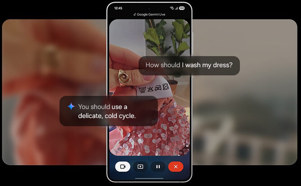 Na ekranie smartfona widać aplikację Google Gemini Live, która pokazuje zdjęcie metki z symbolami prania oraz teksty: \'How should I wash my dress?\' i \'You should use a delicate, cold cycle.\'.