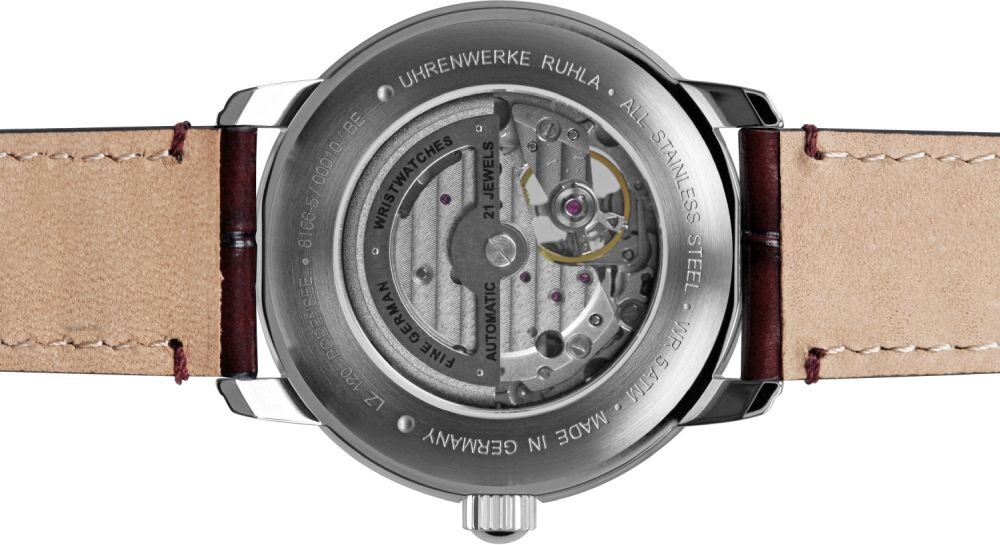 Zdjęcie przedstawia tylną część zegarka z widocznym mechanizmem automatycznym. Na obudowie widnieje napis: \'UHRENWERKE RUHLA - ALL STAINLESS STEEL - 5 ATM - MADE IN GERMANY - 21 JEWELS - AUTOMATIC\'.