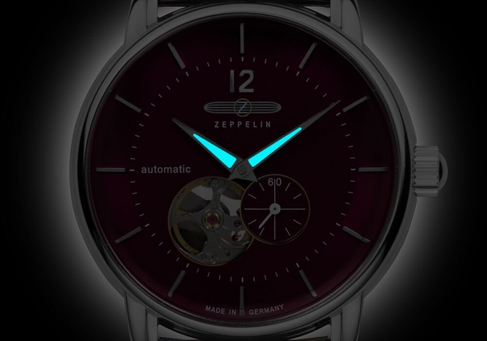 Zegarek z ciemną tarczą, na której widoczne są świecące wskazówki oraz logo \'ZEPPELIN\'. Na tarczy znajduje się napis \'automatic\' i \'MADE IN GERMANY\'.