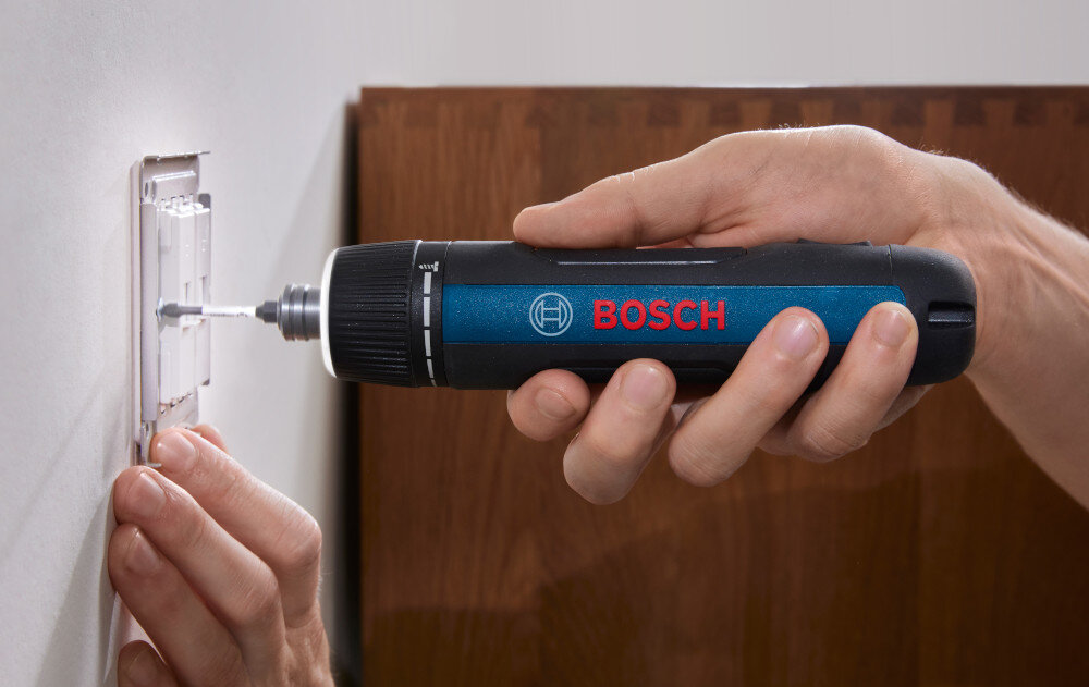 Osoba używa wkrętaka akumulatorowego marki BOSCH do montażu elementu na ścianie. Na urządzeniu widoczne jest logo BOSCH.