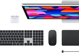 Na obrazie widoczny jest laptop z kolorowym ekranem, klawiatura, mysz oraz słuchawki bezprzewodowe. Produkty są ułożone na białym tle.