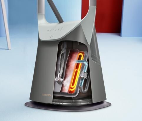 Obraz przedstawia system do prasowania z widocznym wnętrzem, w którym znajdują się elementy grzewcze i rury. Na urządzeniu widoczne jest logo \'PHILIPS\'.