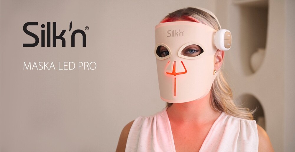 Osoba nosi maskę LED w kolorze jasnym z pomarańczowymi elementami świetlnymi, na której widnieje napis \'Silk\'n\'. Obok maski znajduje się tekst: \'MASKA LED PRO\'.