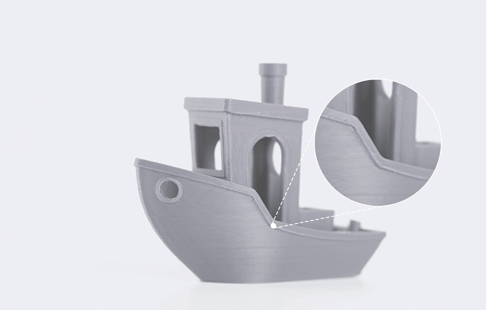 Szary model statku wydrukowany w technologii 3D z widocznym zbliżeniem na szczegół kadłuba. Model ma okrągłe okno i komin na górze.