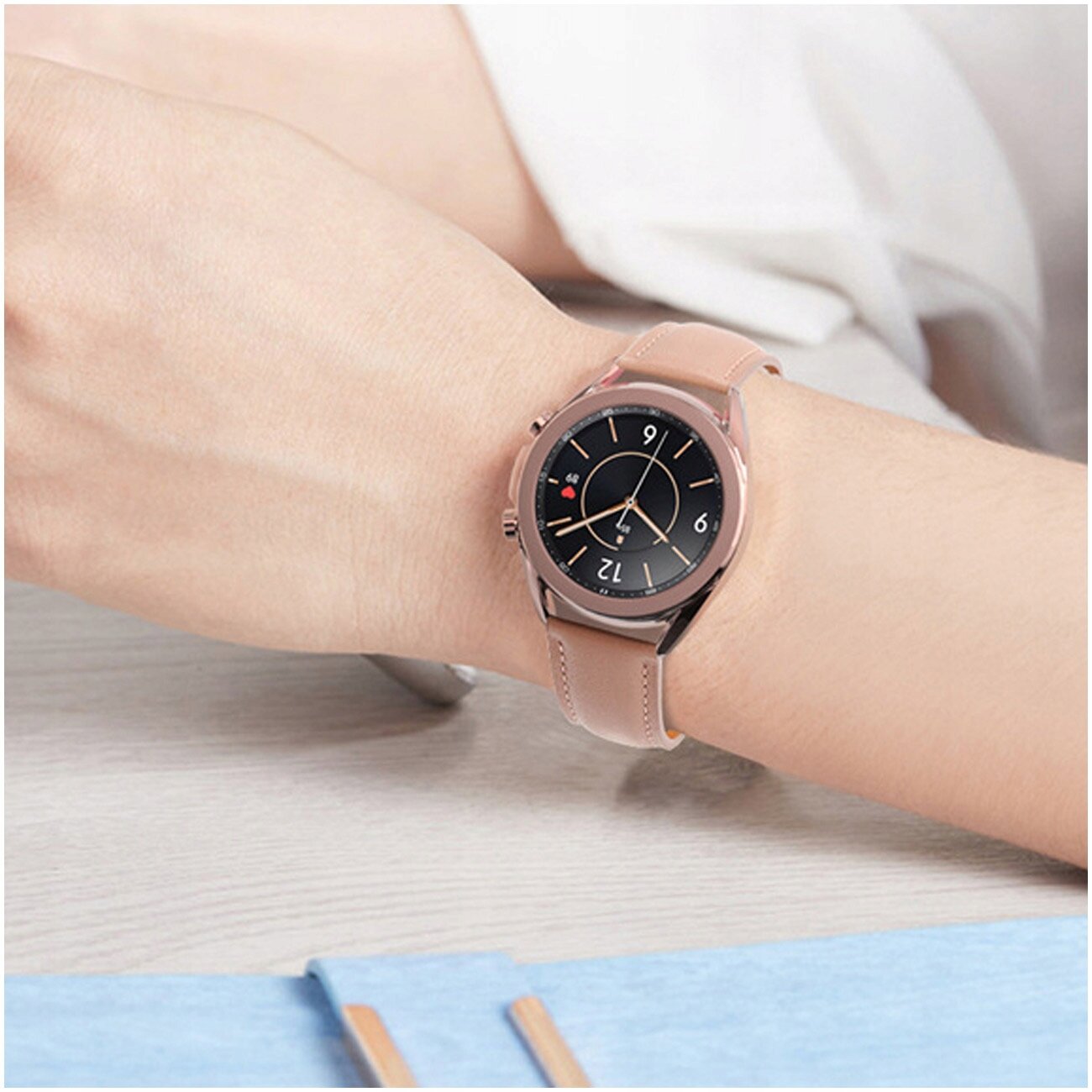 Osoba nosi smartwatch z okrągłą tarczą i skórzanym paskiem w jasnym kolorze. Tarcza zegarka ma ciemne tło z jasnymi wskazówkami i cyframi.