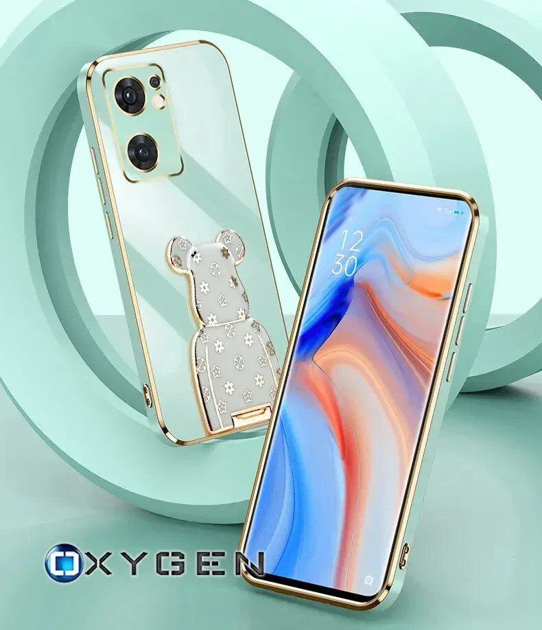 Na obrazie widoczne są dwa telefony w etui z metalicznymi krawędziami, jeden z nich ma ozdobę w kształcie misia. W lewym dolnym rogu znajduje się logo \'OXYGEN\'.