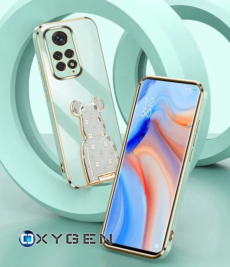 Obraz przedstawia dwa telefony w etui z metalicznymi krawędziami, jeden z nich ma uchwyt w kształcie misia. Na dole widoczne jest logo \'OXYGEN\'.