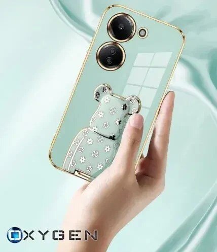 Etui na telefon w kolorze miętowym z motywem misia i złotymi akcentami, trzymane w dłoni. Widoczne logo: OXYGEN.