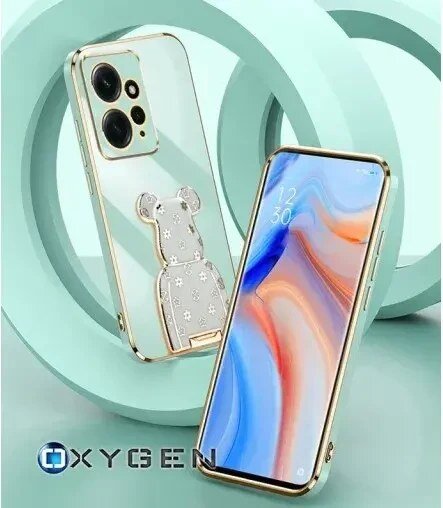 Na obrazie widoczne są dwa telefony w etui z przezroczystym tyłem i złotymi krawędziami, jeden z nich ma ozdobę w kształcie misia. W tle znajdują się geometryczne kształty w kolorze miętowym, a na dole widnieje logo \'OXYGEN\'.