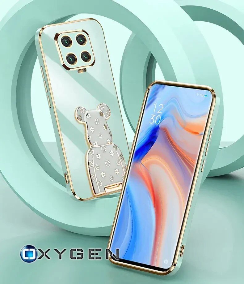 Obraz przedstawia dwa telefony w etui z przezroczystym tyłem i złotymi krawędziami, z widocznym uchwytem w kształcie misia. Na dole widoczne jest logo \'OXYGEN\'.