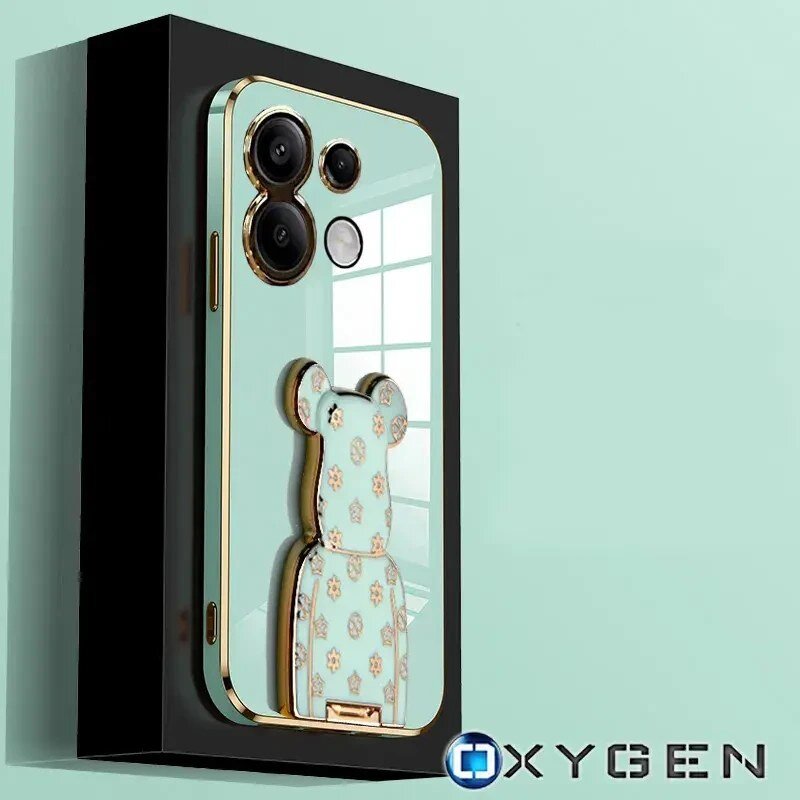 Etui na telefon w kolorze miętowym z ozdobnym uchwytem w kształcie misia i złotymi akcentami. Widoczne logo: OXYGEN.