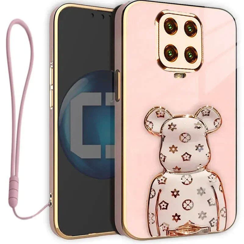 Etui na telefon w kolorze różowym z ozdobnym uchwytem w kształcie misia z wzorami. Obok znajduje się różowa smycz do telefonu.