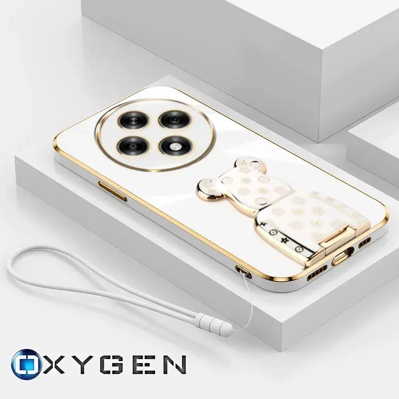 Na obrazie widoczne jest białe etui na telefon z trzema okrągłymi otworami na aparat oraz ozdobnym uchwytem w kształcie misia. W dolnej części znajduje się logo \'OXYGEN\' oraz przymocowana smycz.