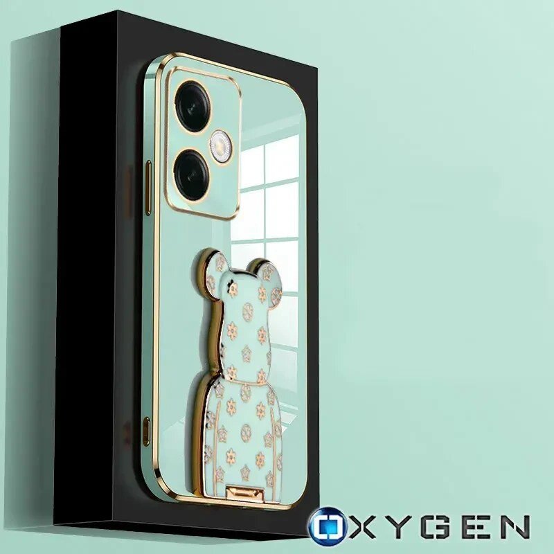 Obraz przedstawia etui na telefon w kolorze miętowym z ozdobnym uchwytem w kształcie misia. W prawym dolnym rogu widoczne jest logo \'OXYGEN\'.