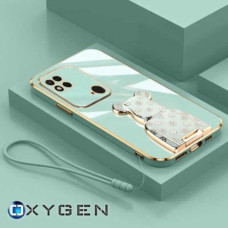 Na obrazie znajduje się etui na telefon w kolorze miętowym z ozdobnym uchwytem w kształcie misia. W dolnej części widoczne jest logo \'OXYGEN\'.