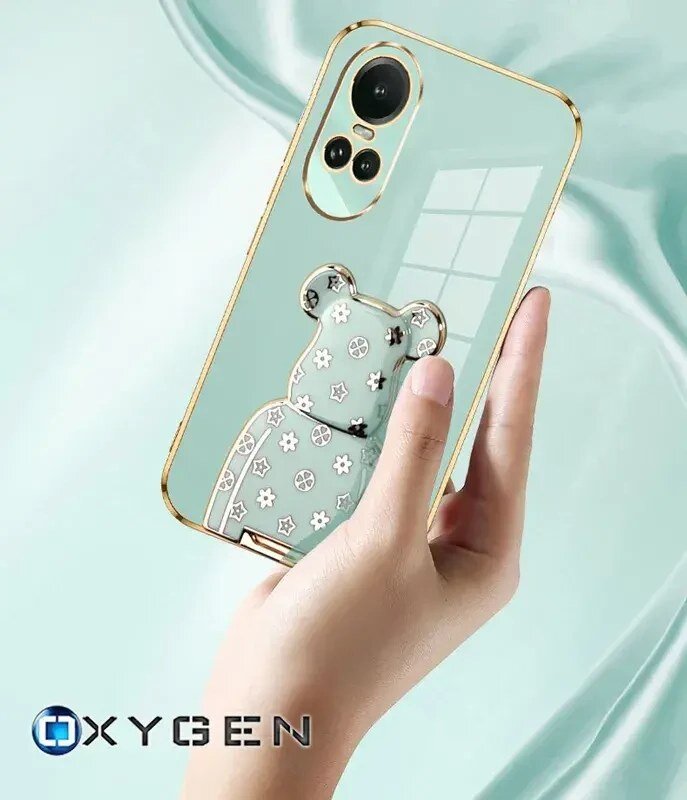 Osoba trzyma etui na telefon z motywem misia i kwiatów, z widocznymi otworami na aparat. Na dole widoczne jest logo \'OXYGEN\'.