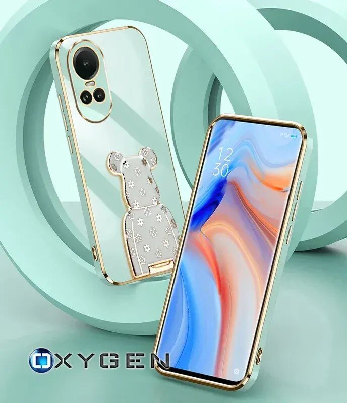 Obraz przedstawia dwa telefony w etui z przezroczystym tyłem i złotymi krawędziami, z widocznym uchwytem w kształcie misia. Na dole widoczne jest logo \'OXYGEN\'.