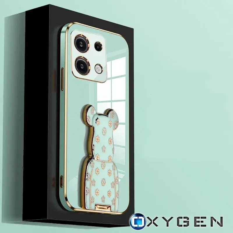 Obraz przedstawia etui na telefon z motywem misia, z trzema dużymi otworami na aparaty. W prawym dolnym rogu widoczne jest logo \'OXYGEN\'.