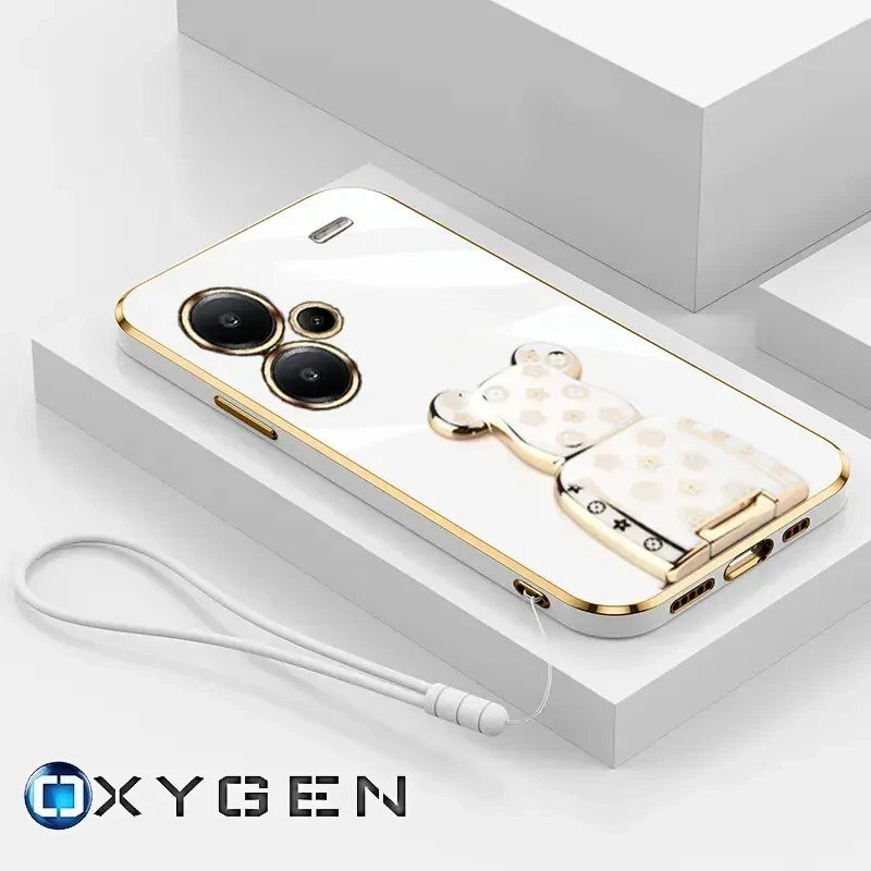 Na obrazie widoczne jest białe etui na telefon z dwoma dużymi otworami na aparaty oraz uchwytem w kształcie misia. W dolnej części znajduje się logo \'OXYGEN\' oraz biała smycz przymocowana do etui.