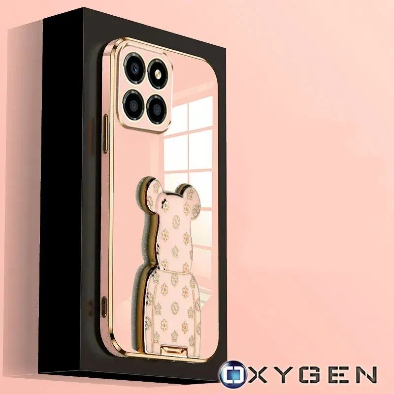 Etui na telefon z motywem misia i czterema otworami na aparat, w kolorze złotym z wzorami. W prawym dolnym rogu widoczne jest logo OXYGEN.