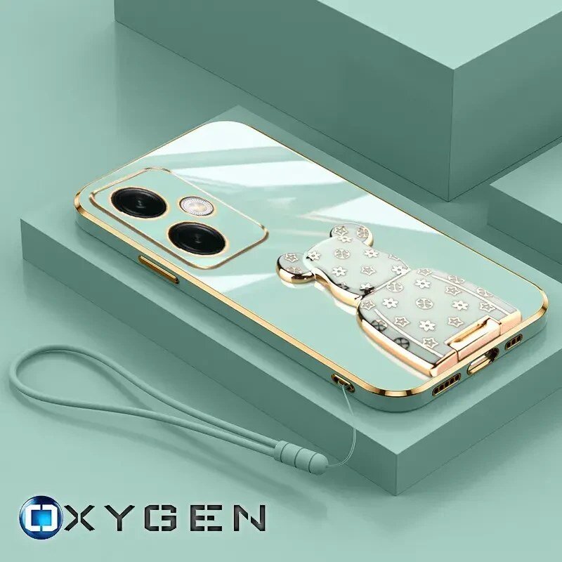 Etui na telefon w kolorze miętowym z ozdobnym uchwytem w kształcie misia i złotymi akcentami. Widoczne logo: OXYGEN.
