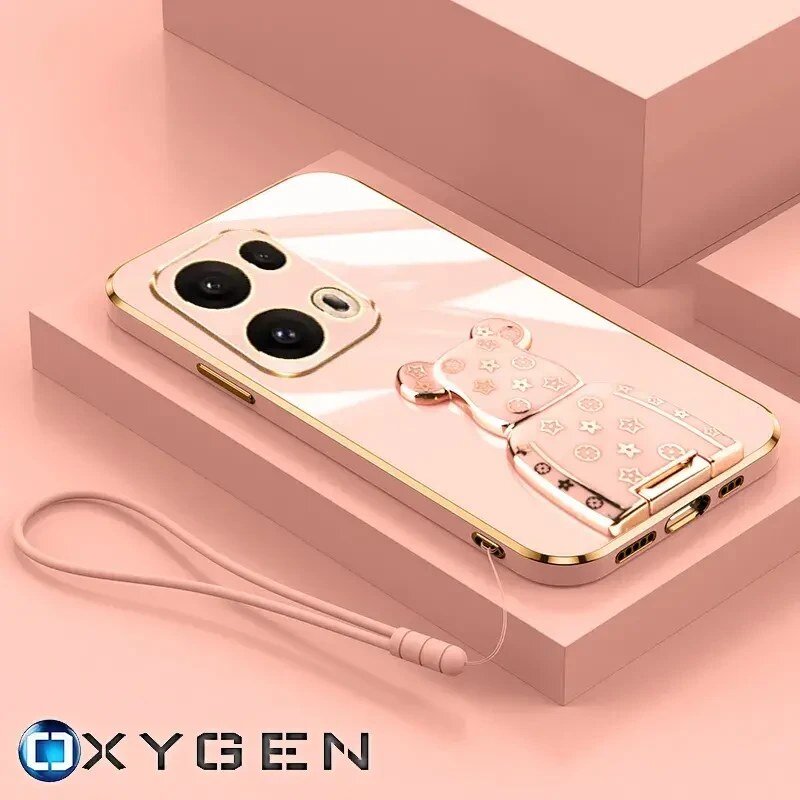Na obrazie widoczne jest różowe etui na telefon z uchwytem w kształcie misia, ozdobionym wzorami gwiazdek i kwiatków. W dolnej części obrazu znajduje się logo \'OXYGEN\'.