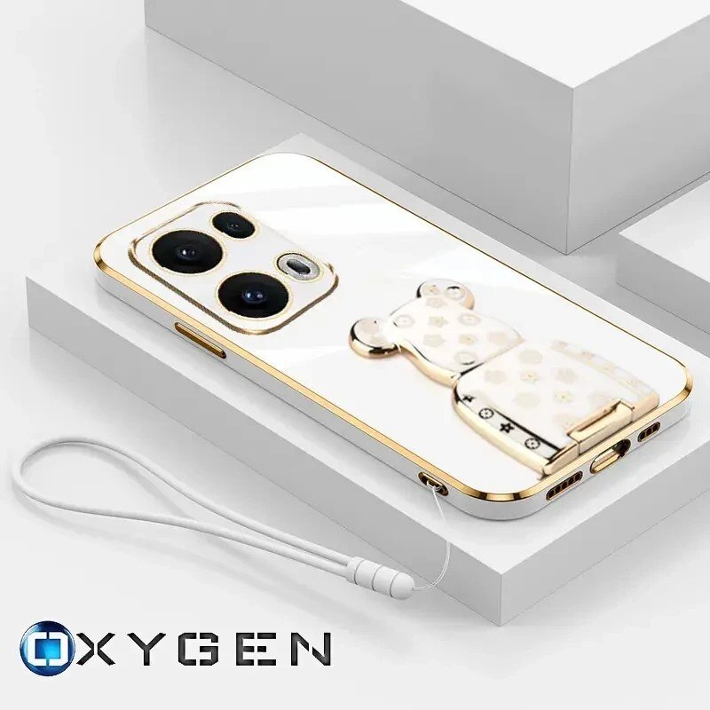 Na obrazie widoczne jest etui na telefon z metalicznymi krawędziami i ozdobnym uchwytem w kształcie misia. W dolnej części znajduje się logo \'OXYGEN\'.