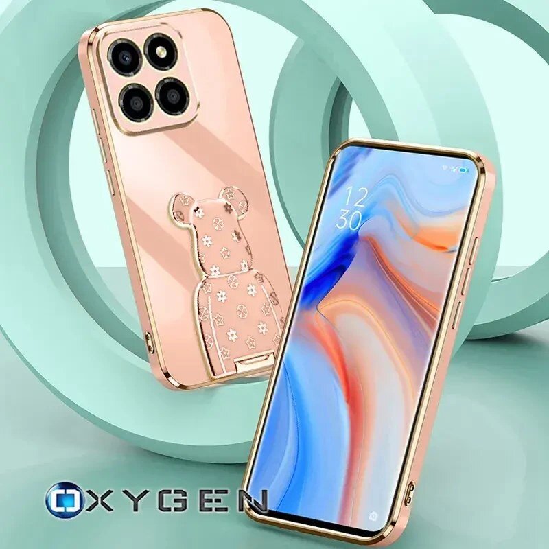 Obraz przedstawia różowe etui na telefon z wytłoczonym wzorem misia i czterema okrągłymi otworami na aparaty. Obok znajduje się telefon z kolorowym wyświetlaczem, a w lewym dolnym rogu widoczne jest logo \'OXYGEN\'.