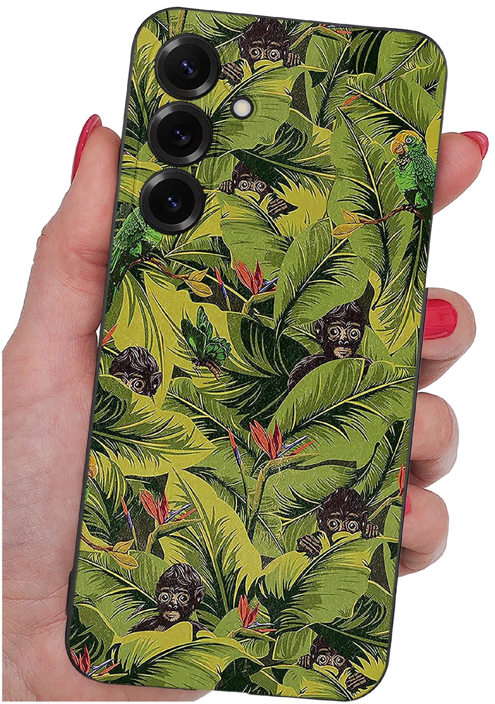 Etui na telefon z wzorem przedstawiającym zielone liście i małpy, trzymane w dłoni z czerwonym lakierem na paznokciach. Etui posiada trzy otwory na aparaty fotograficzne.