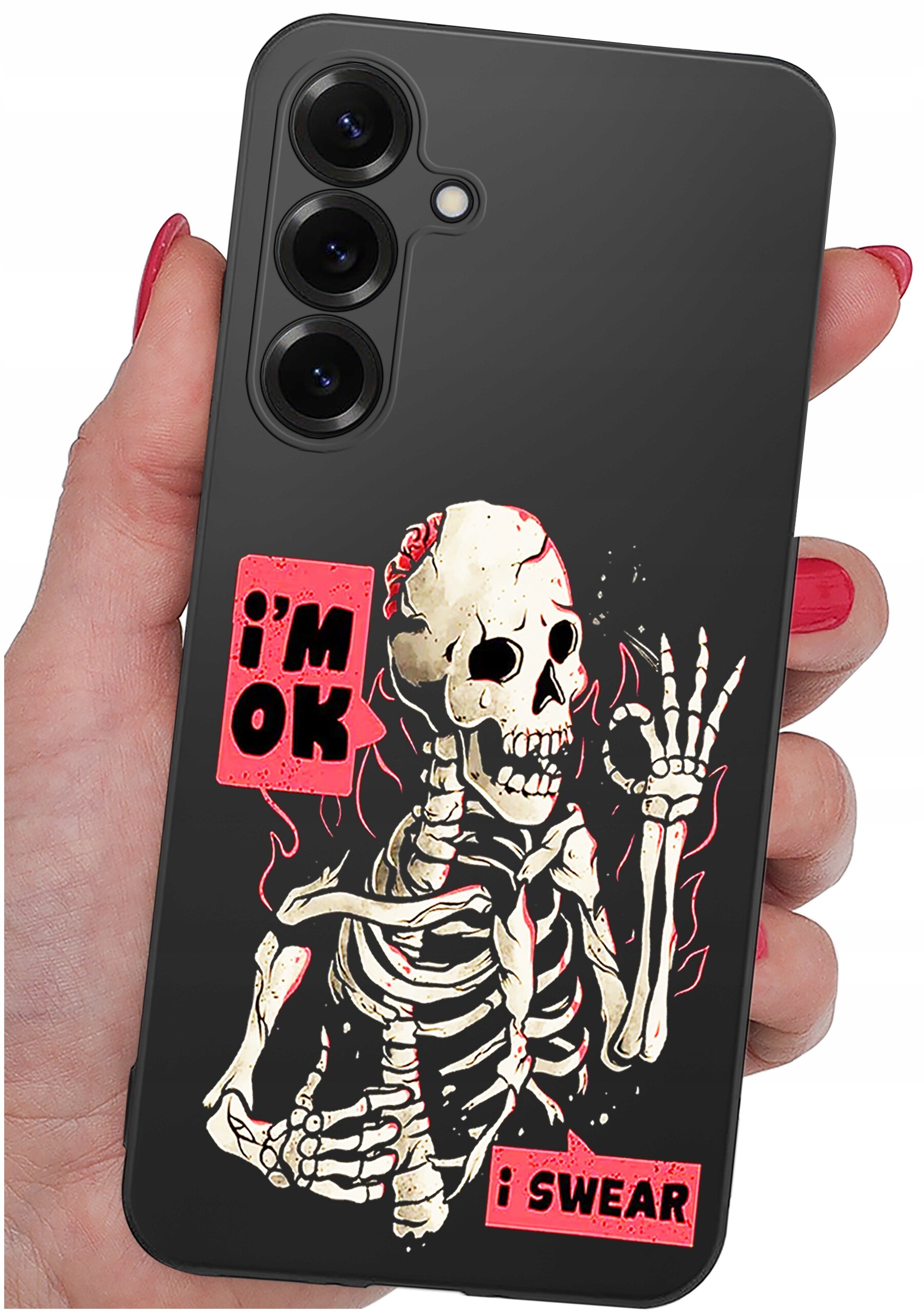 Etui na telefon z grafiką szkieletu i napisami \'i\'m OK\' oraz \'i SWEAR\'. Etui jest trzymane w dłoni z pomalowanymi na czerwono paznokciami.