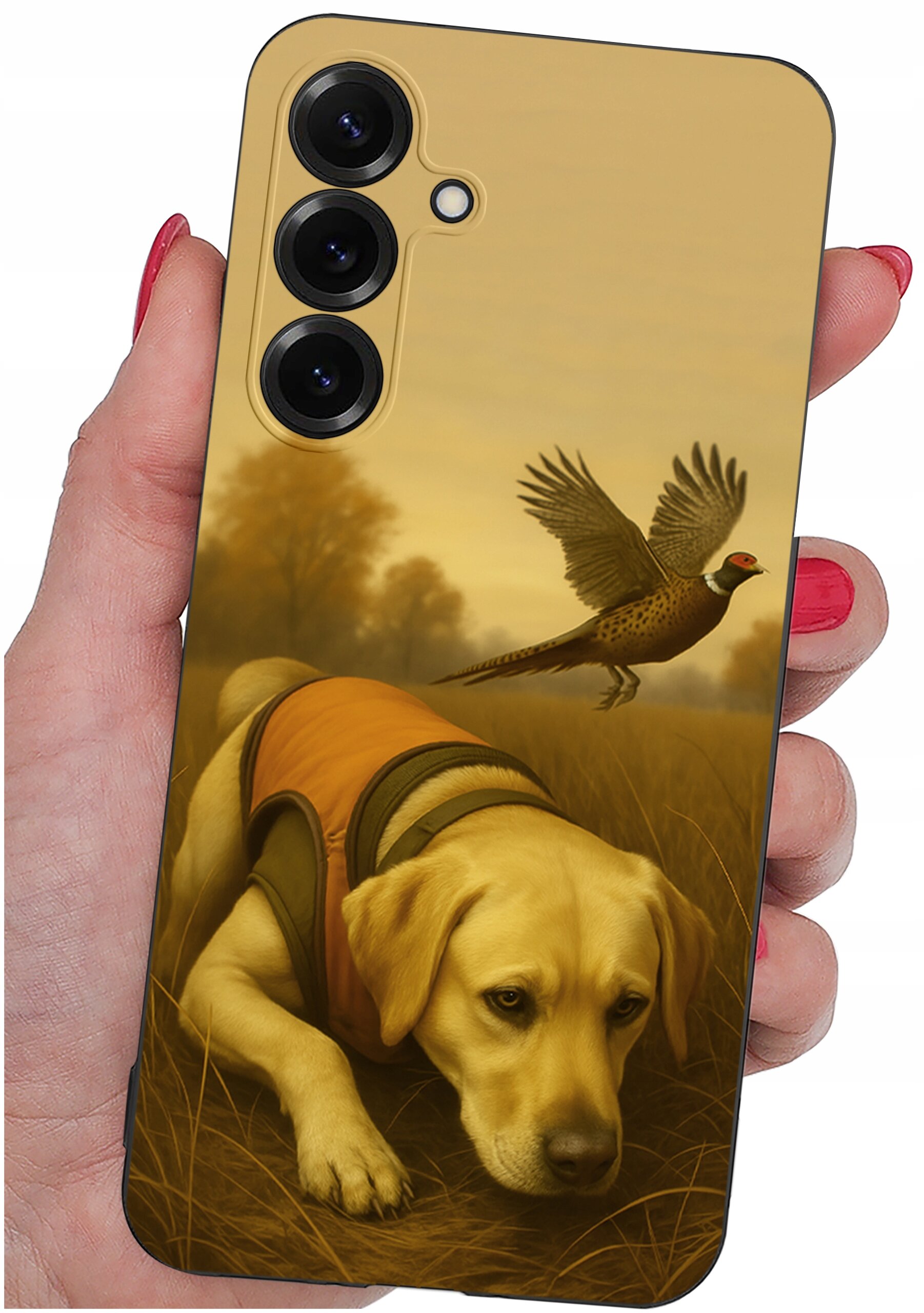 Etui na telefon z nadrukiem psa w pomarańczowej kamizelce i lecącego ptaka na tle jesiennego krajobrazu. Etui trzymane jest w dłoni z pomalowanymi na czerwono paznokciami.