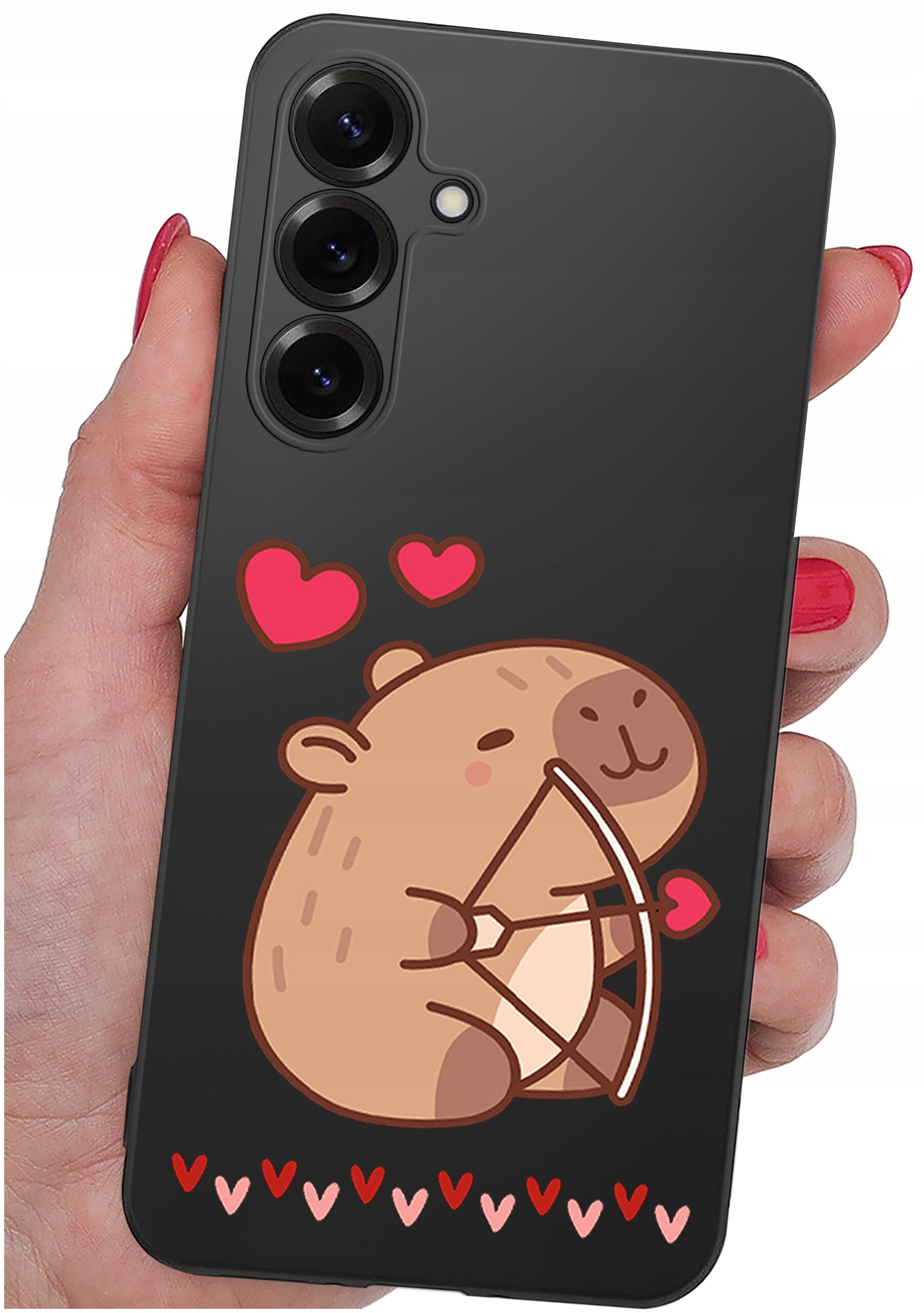 Czarne etui na telefon z grafiką przedstawiającą uśmiechniętego zwierzątka trzymającego łuk z sercem oraz czerwonymi serduszkami wokół. Etui jest trzymane w dłoni z pomalowanymi na czerwono paznokciami.