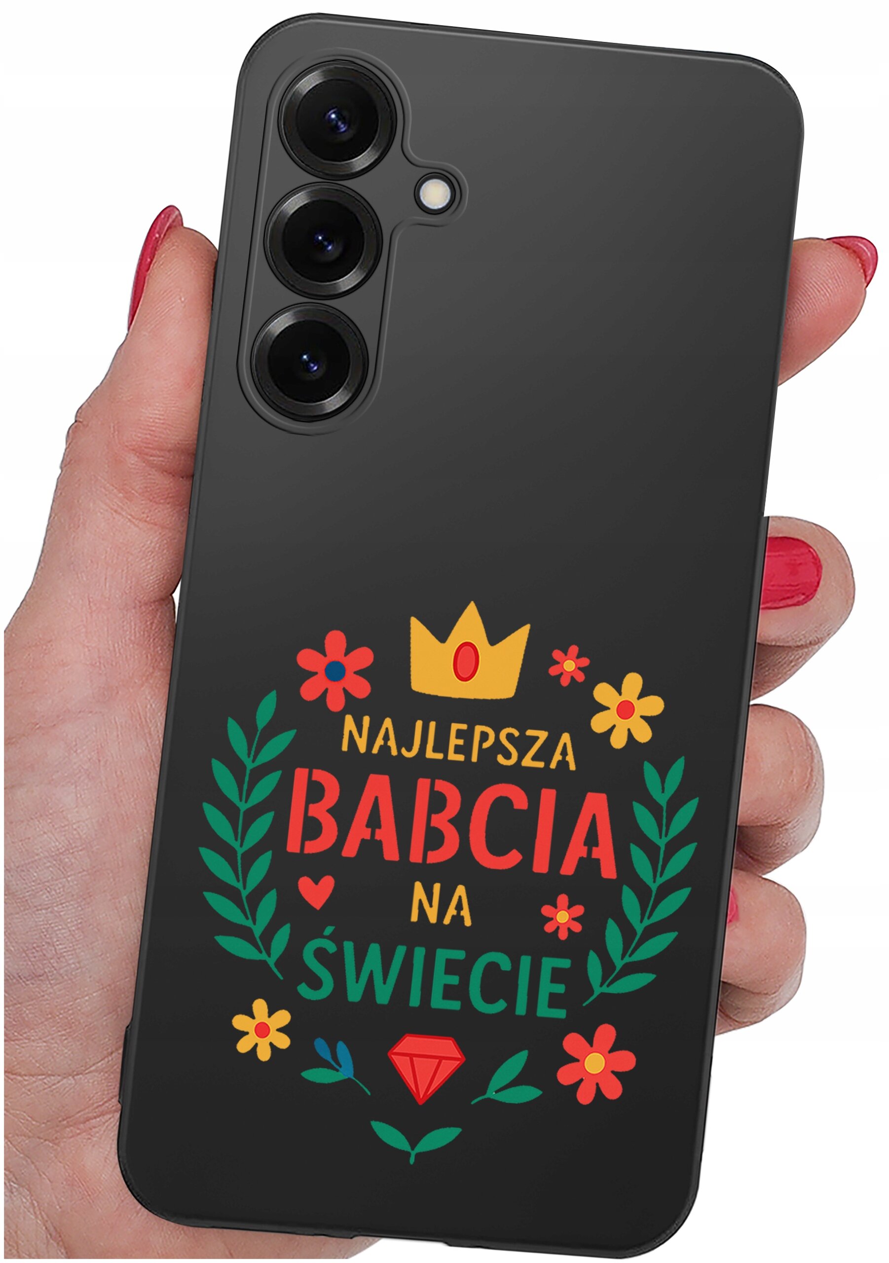 Czarna obudowa telefonu z kolorowym napisem \'NAJLEPSZA BABCIA NA ŚWIECIE\' otoczonym kwiatami i liśćmi. Obudowa jest trzymana w dłoni z pomalowanymi na czerwono paznokciami.