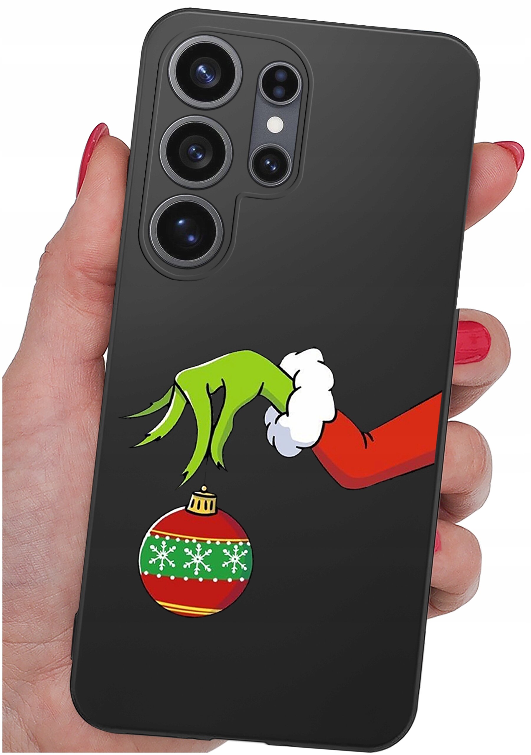 Czarne etui na telefon z grafiką przedstawiającą zieloną rękę trzymającą czerwoną bombkę świąteczną z zielonym paskiem i białymi śnieżynkami. Etui jest trzymane w dłoni z pomalowanymi na czerwono paznokciami.