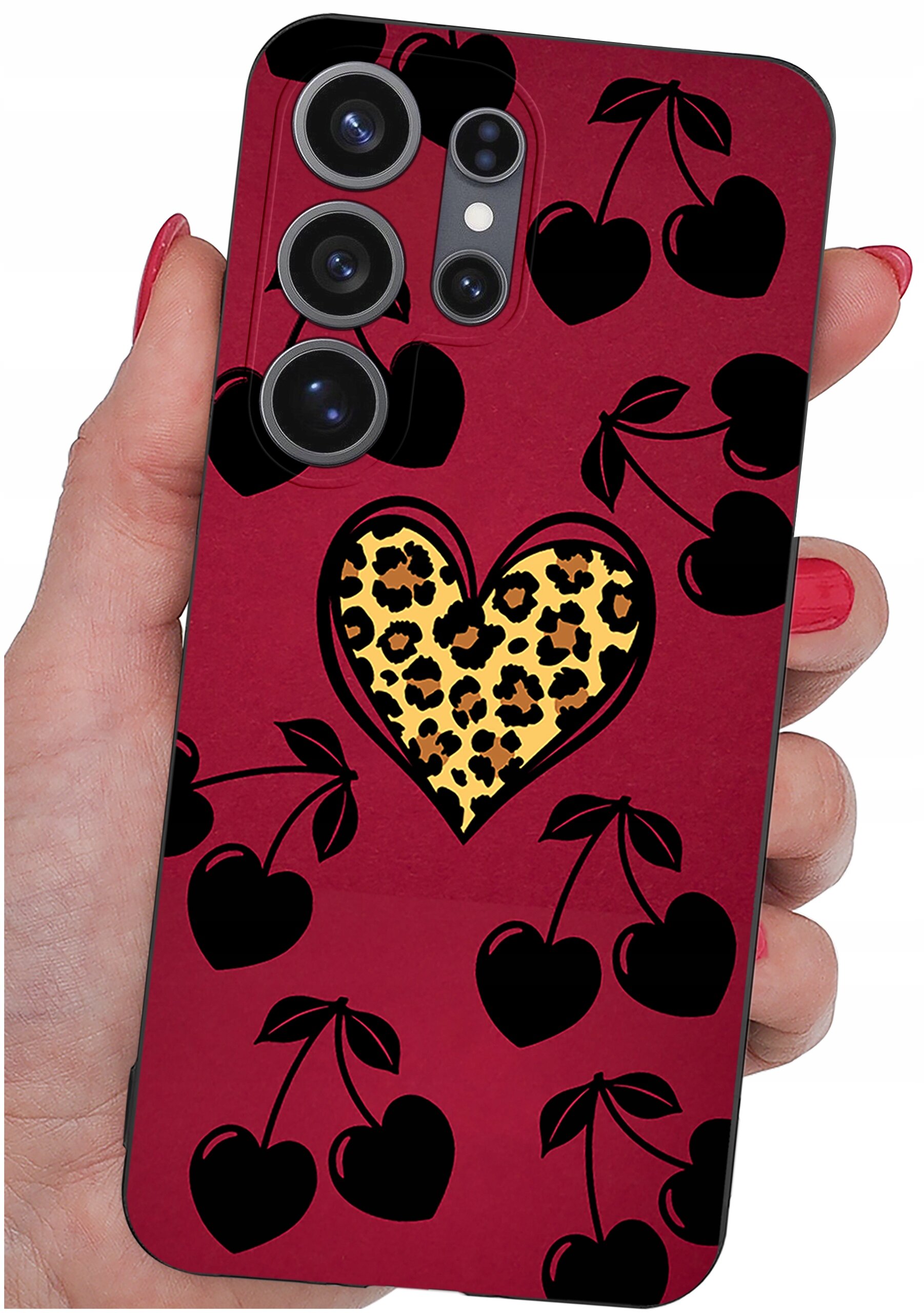 Etui na telefon w kolorze bordowym z czarnymi wzorami serc i wisienek oraz centralnym sercem z motywem panterki. Etui trzymane jest w dłoni z pomalowanymi na czerwono paznokciami.