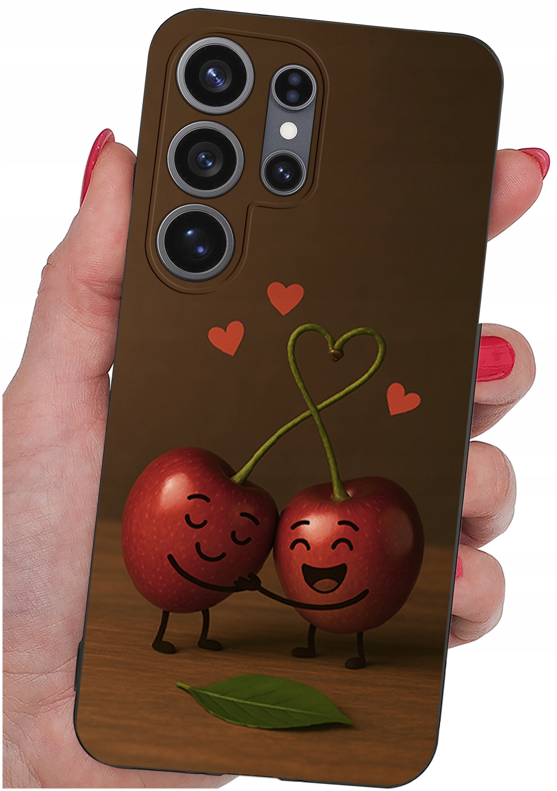 Etui na telefon z grafiką przedstawiającą dwie uśmiechnięte wiśnie z połączonymi ogonkami w kształcie serca, otoczone małymi serduszkami. Etui trzymane jest w dłoni z pomalowanymi na czerwono paznokciami.