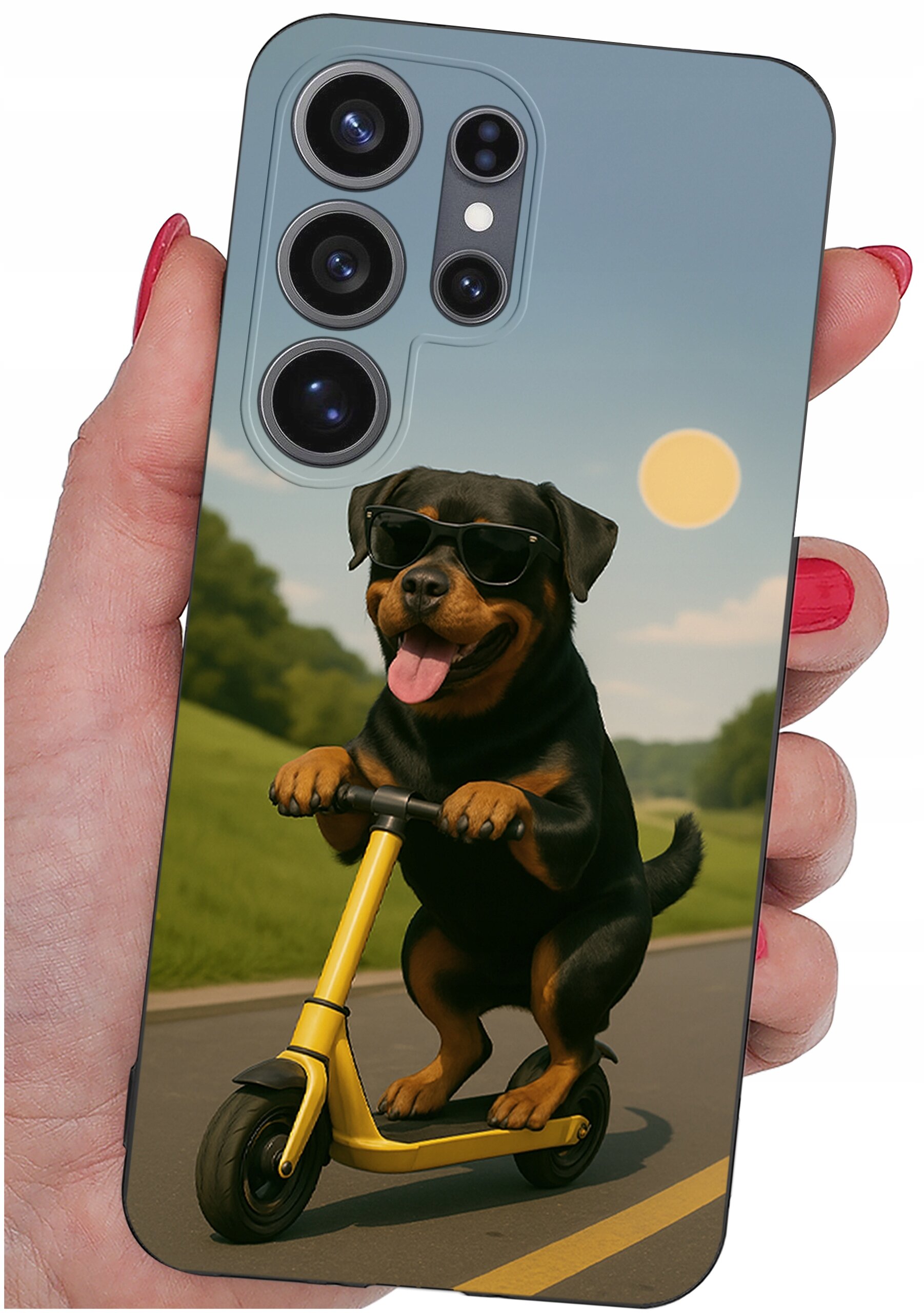 Etui na telefon z nadrukiem psa w okularach przeciwsłonecznych, jadącego na żółtej hulajnodze po drodze. W tle widoczny jest krajobraz z zielonymi drzewami i jasnym niebem.