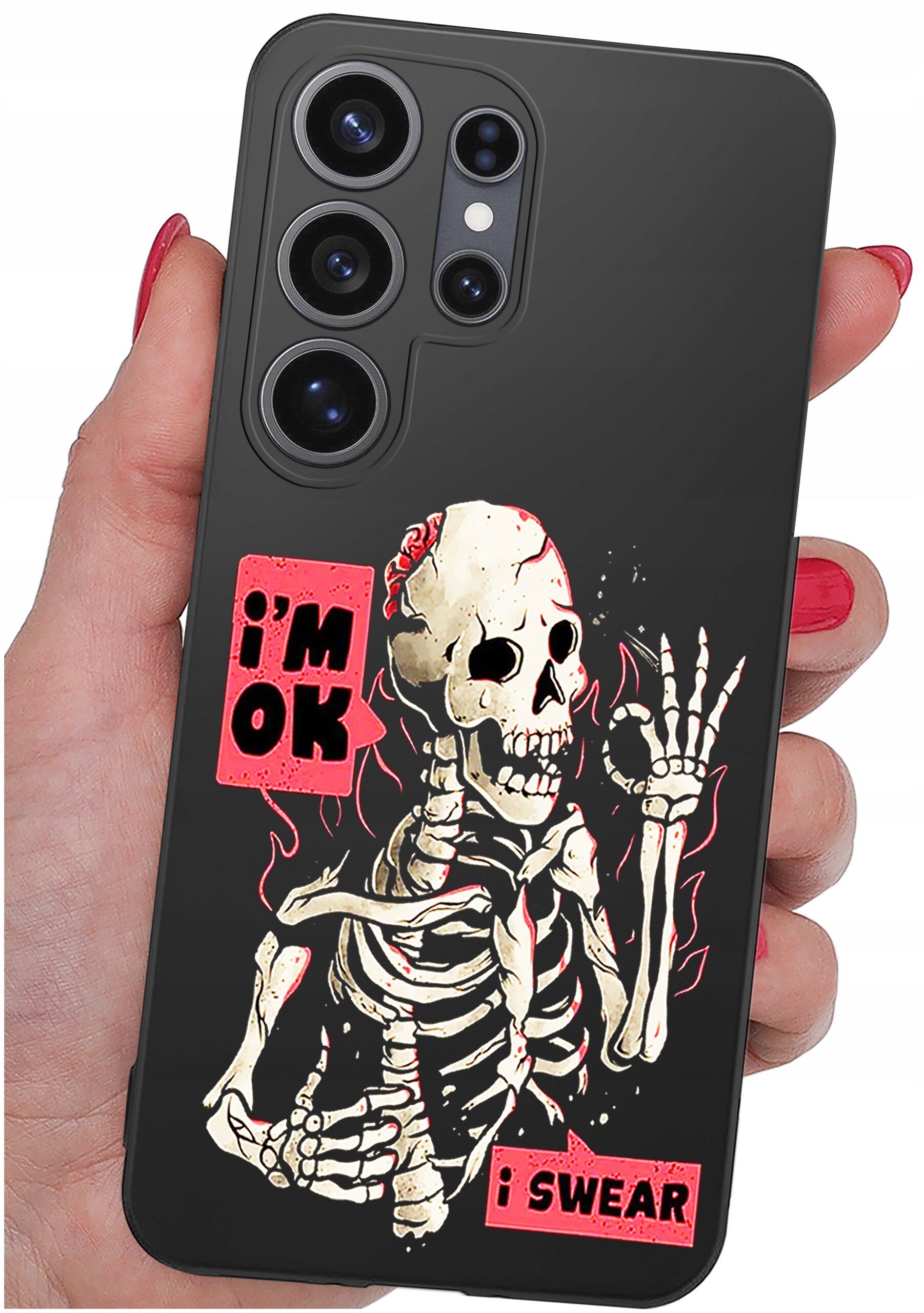 Etui na telefon z grafiką szkieletu i napisami \'i\'m OK\' oraz \'i SWEAR\'. Etui jest trzymane w dłoni z pomalowanymi na czerwono paznokciami.