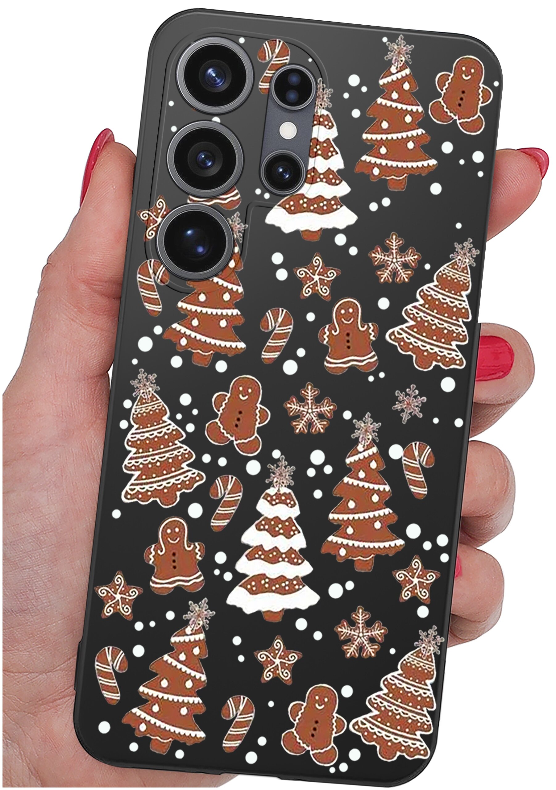 Etui na telefon z czarnym tłem ozdobione wzorami pierników w kształcie choinek, ludzików i lasek cukrowych. Etui trzymane jest w dłoni z pomalowanymi na czerwono paznokciami.